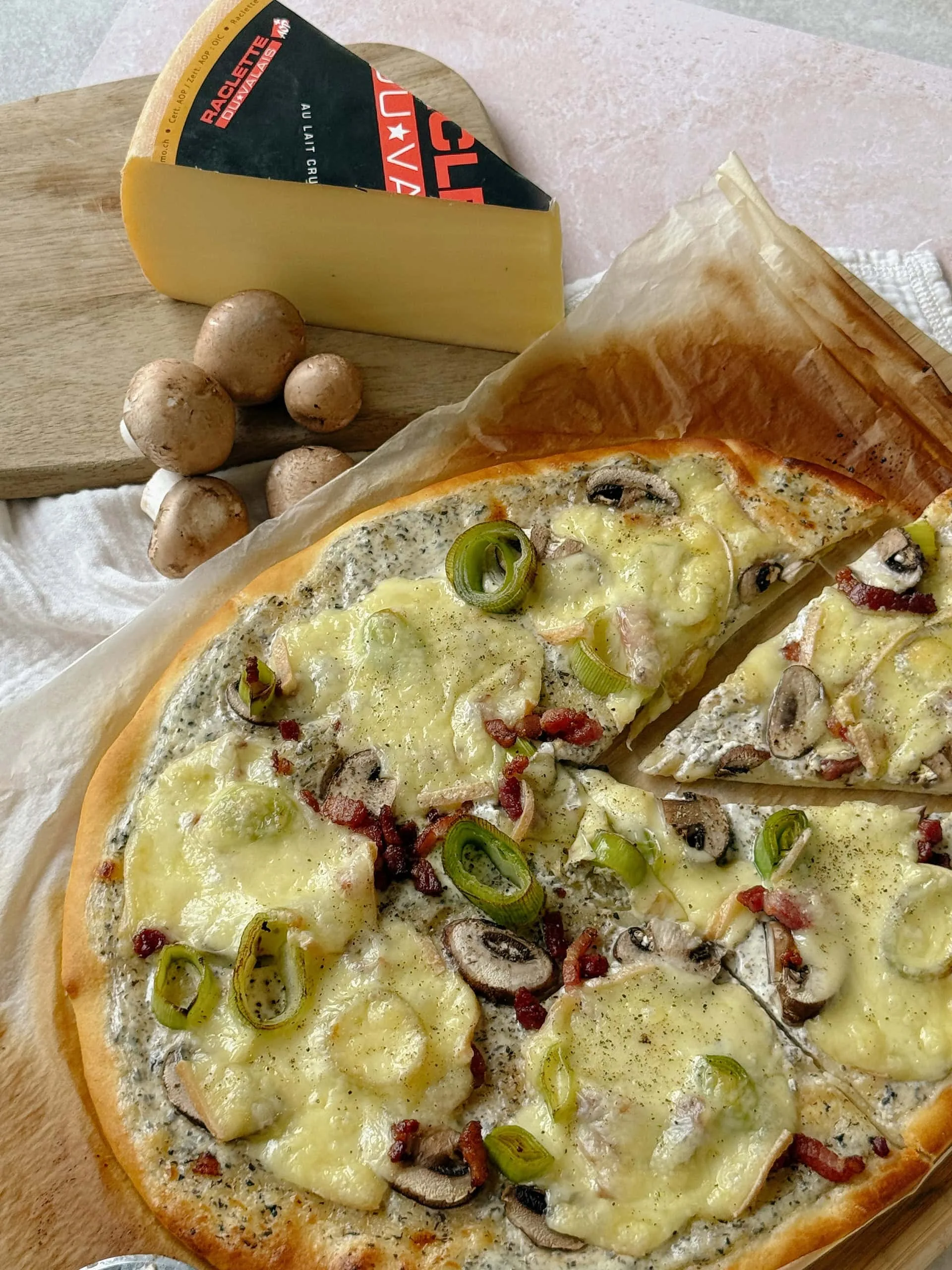 Pizza blanche, fondue de poireaux à la tapenade de truffe, champignons et Raclette du Valais AOP